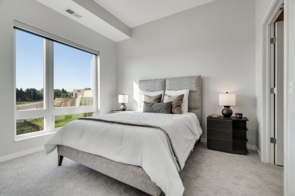 Furnished bedroom with high ceiling, large window and connected bathroom