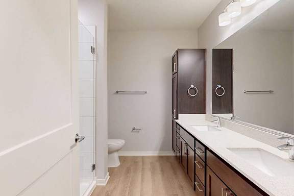 A bathroom with a toilet, sink, and mirror.