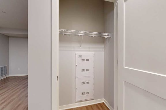 A white closet with a shelf and a white door.