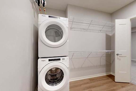 Two washing machines are stacked on top of each other in a laundry room.