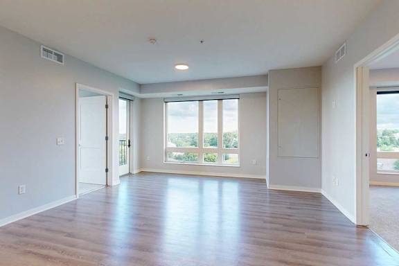 A spacious room with wooden floors and large windows.