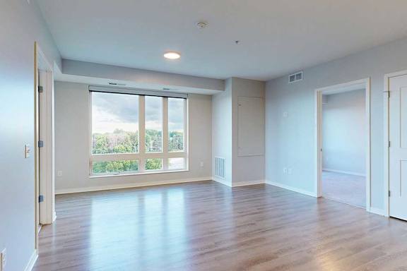 A large empty room with wooden floors and a sliding glass door.