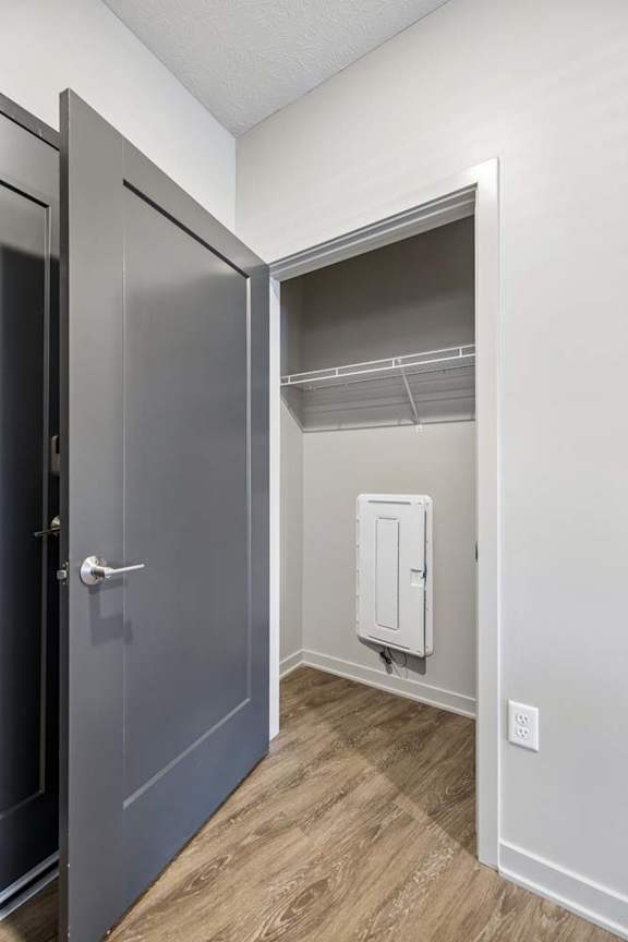 Entryway storage closet with wire shelving, wood-look flooring, and easy access from the apartment foyer.