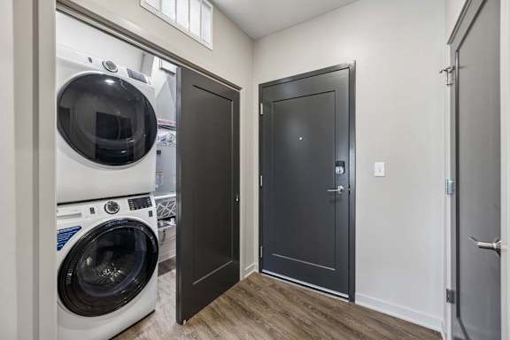 In-home laundry area with a stacked washer and dryer, wood-look flooring, and convenient access from the main living space.