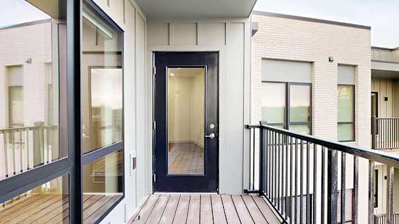 a balcony with a black windowed door to the living room and a window into the bedroom