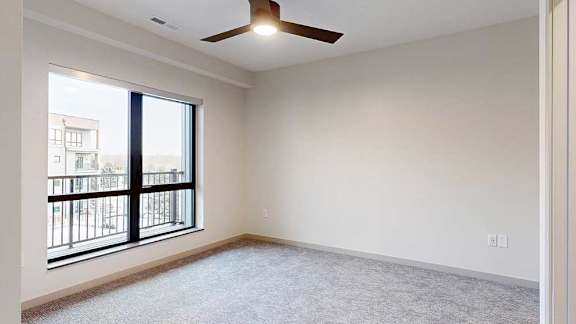 a bedroom with a large window, a ceiling fan, and carpeted flooring