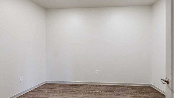 a den space with hardwood flooring and white walls
