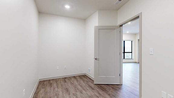 a den space with hardwood flooring and a door to the living room