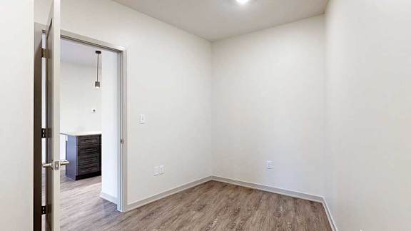 a den space with hardwood flooring and white walls