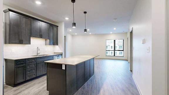 an open concept living room and kitchen with dark wood cabinets and light quartz countertops