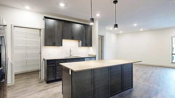 a modern kitchen with dark cabinets, stainless steel appliances, and a large central island
