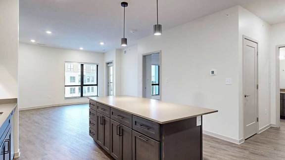 a large kitchen island with quartz countertops in front of a spacious living room