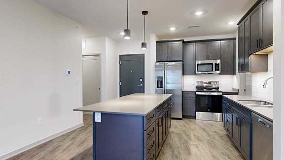 a modern kitchen with dark wooden cabinets, stainless steel appliances, quartz countertops, and a large central island