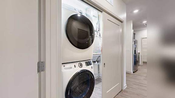 a stackable washer and dryer in a double door closet in the front hallway