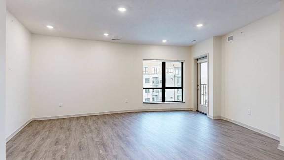 a spacious living room with a large window and a windowed door to a balcony