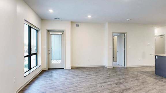 a spacious living room with wood flooring and white walls