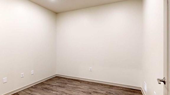 a den space with hardwood floors and white walls