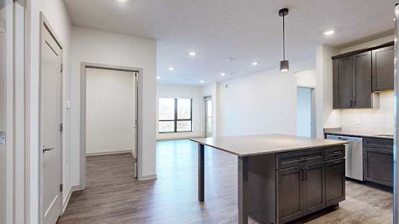 a modern kitchen with a large central island and a door to the den space