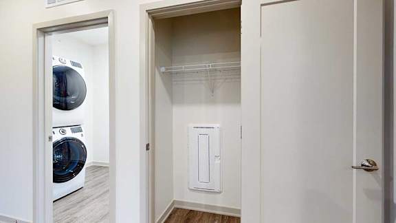 a coat closet in the front entryway next to a laundry room with a stackable washer and dryer