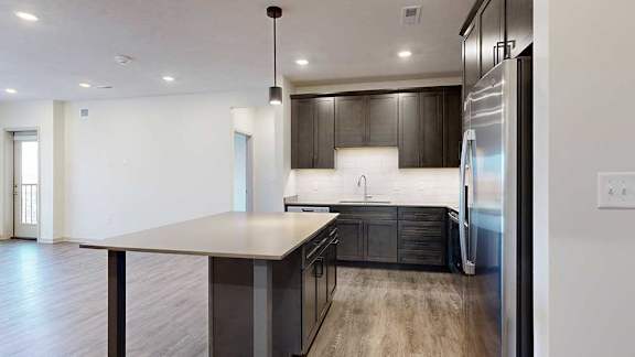 a modern kitchen with dark wooden cabinets, quartz countertops, and a large central island