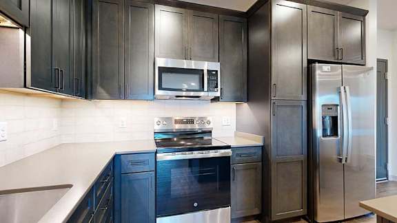 a modern kitchen with dark cabinets and stainless steel appliances