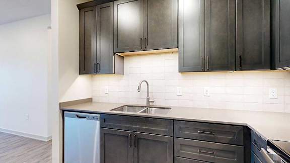 a modern kitchen with dark cabinets and a white tile backsplash