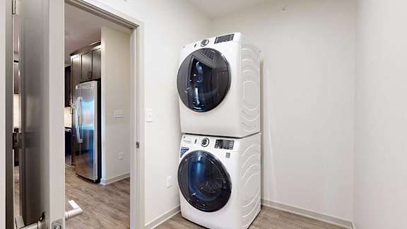 a laundry room with a stackable washer and dryer next to the front door