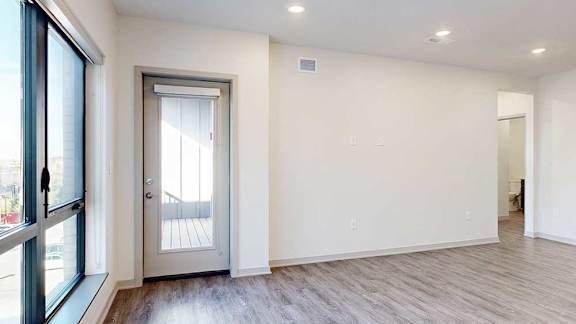 a living room with hardwood flooring and a door to a balcony