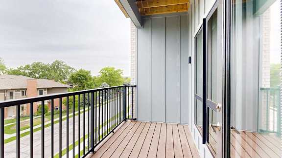 A balcony with a metal railing and a view of the neighborhood.