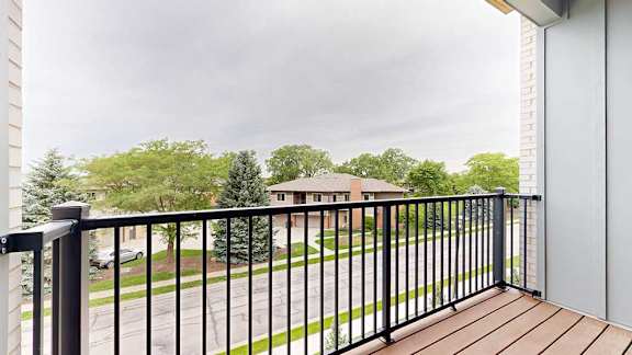 A balcony with a metal railing and a view of the neighborhood.
