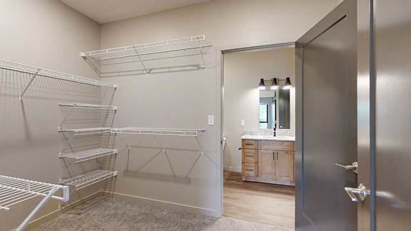 A walk-through closet with wire shelving on either side, and a door open to an attached bathroom.