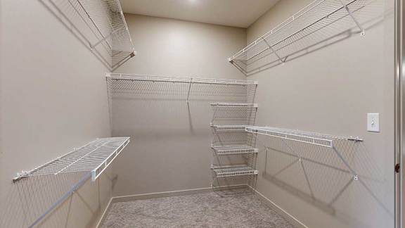 An oversized walk-in closet with several built-in wire shelves.