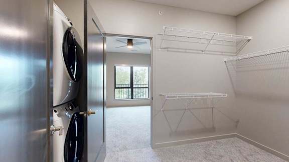 A walk-through closet with wire shelving on either side, and a door open to a bedroom.
