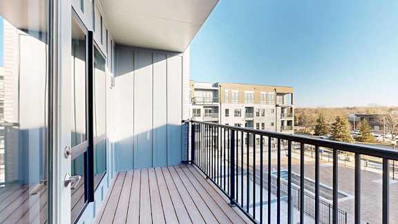 A balcony with a metal railing, overlooking a courtyard.