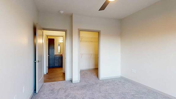 A bedroom with a ceiling fan and a walk-in closet.