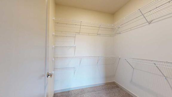 An oversized walk-in closet with several built-in wire shelves.