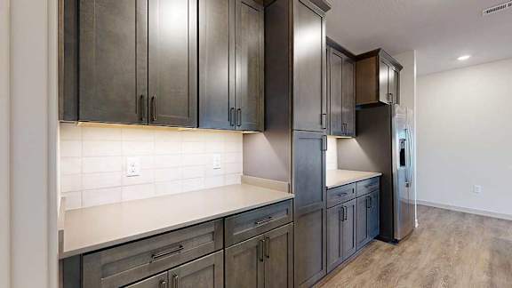 A kitchen with dark wooden cabinets, quartz countertops, an island, and stainless steel appliances.
