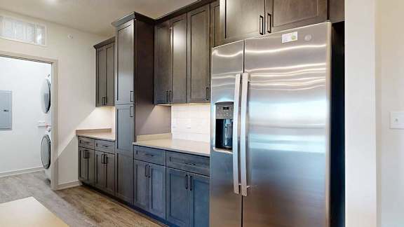 A kitchen with dark wooden cabinets, quartz countertops, an island, and stainless steel appliances.