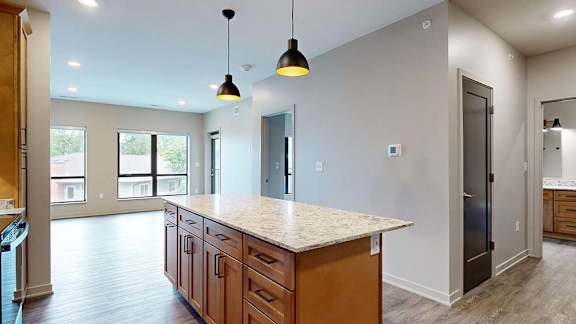 Open apartment kitchen with a large island, pendant lighting, and an open layout to the living area.