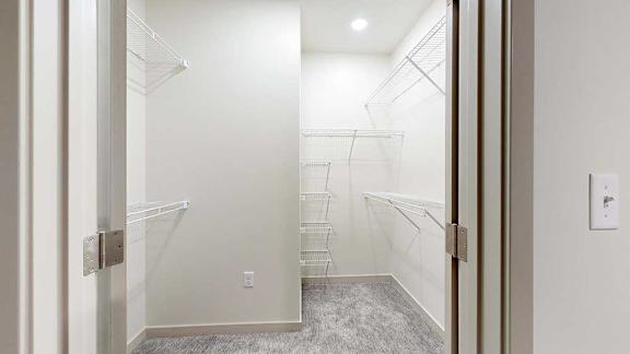 Apartment walk-in shower with glass doors, light tile walls, built-in shelving, and patterned tile flooring.
