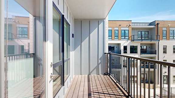 A balcony with a metal railing, overlooking a courtyard.