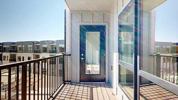 A balcony with a metal railing, overlooking a courtyard.