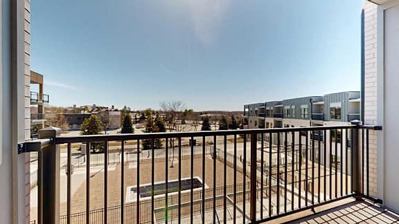 A balcony with a metal railing, overlooking a courtyard.