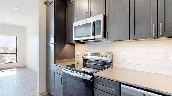 A close up of the stainless steel microwave and range in a kitchen with dark wooden cabinets.