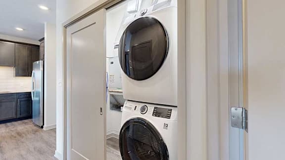 A stacked full-sized washer and dryer in a laundry room.