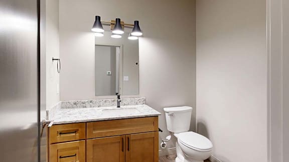 Modern apartment bathroom with a single-sink vanity, wood cabinetry, and a large mirror.