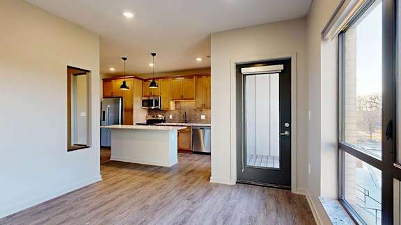 Modern apartment kitchen with a large island, wood cabinetry, and stainless steel appliances.