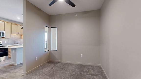 Apartment dining area with carpeted flooring, a ceiling fan, and an open layout next to the kitchen.