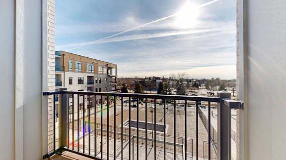A balcony with a metal railing, overlooking a courtyard.