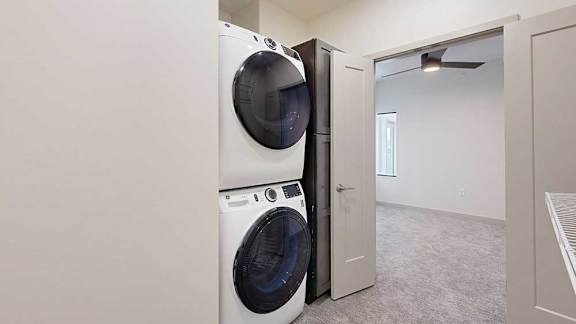 An oversized walk-in closet with wire shelving and a stacked washer and dryer.